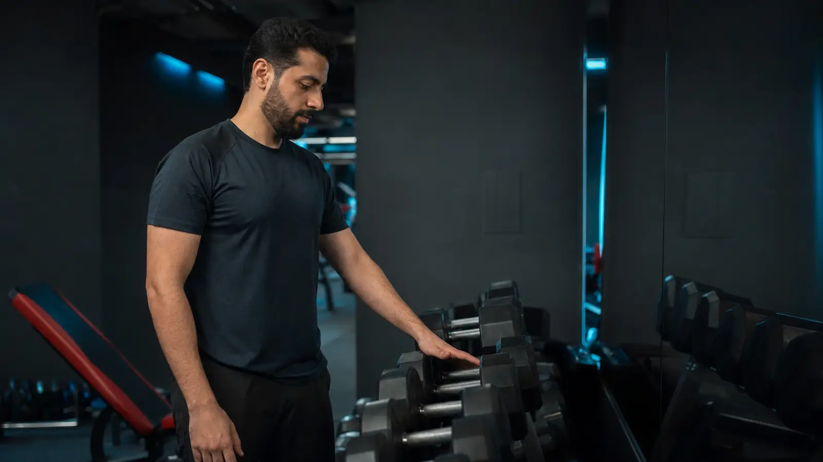 AI-generated editorial close view of an anonymous beginner calmly selecting modest dumbbells from a rack