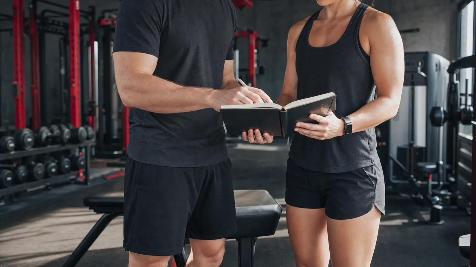 AI-generated editorial photograph of an anonymous coach and trainee reviewing a blank training journal together