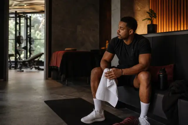 AI-generated editorial image of a strength-training client pausing in a calm wellness setting