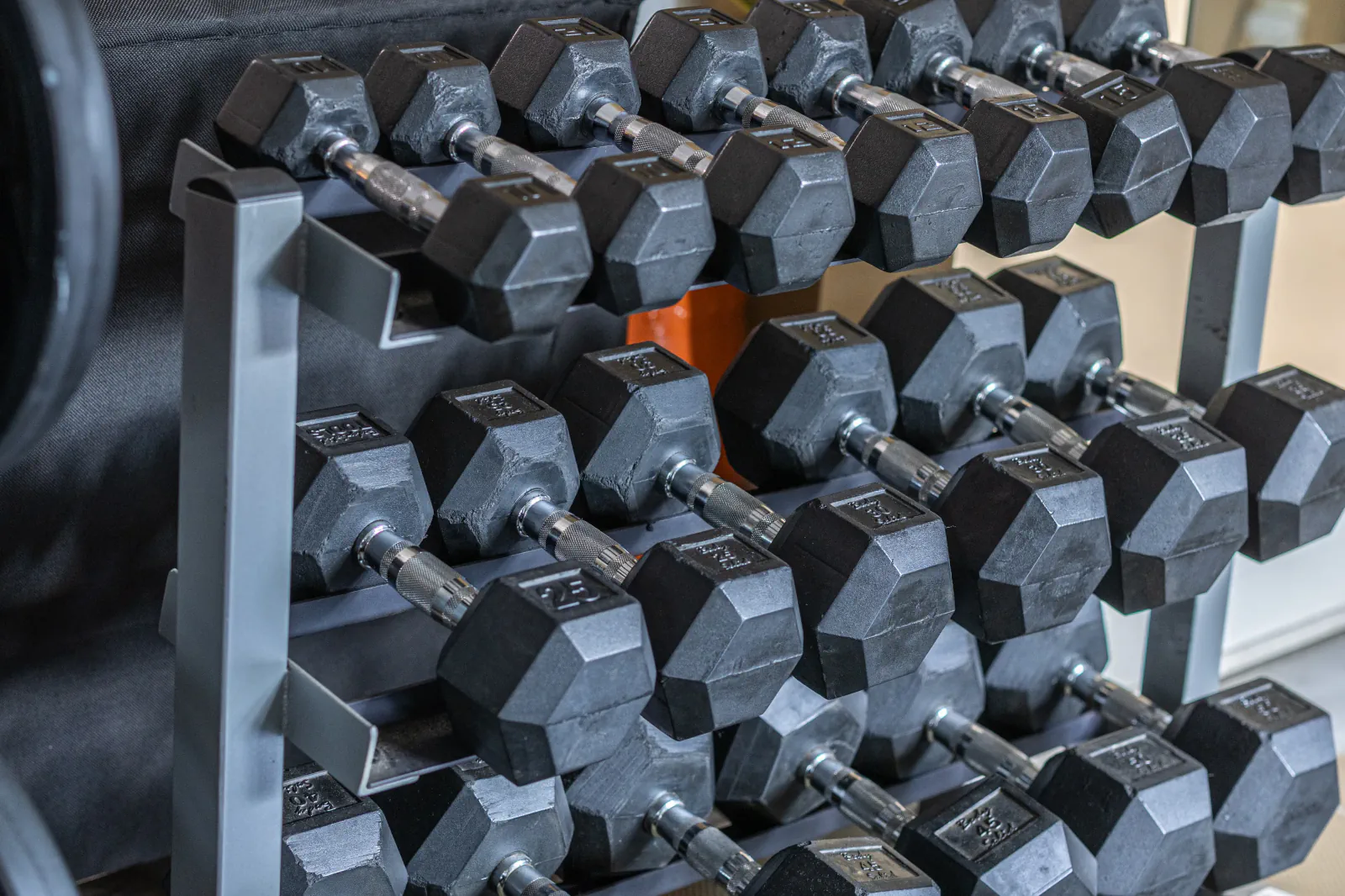 Free-weight selection arranged on a three-tier gym rack