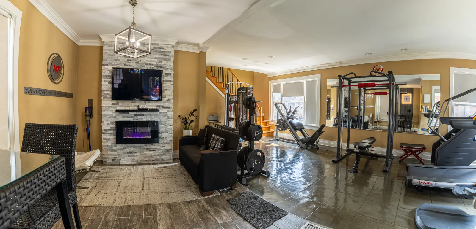 Overall Development gym and lounge with strength equipment, treadmill and fireplace